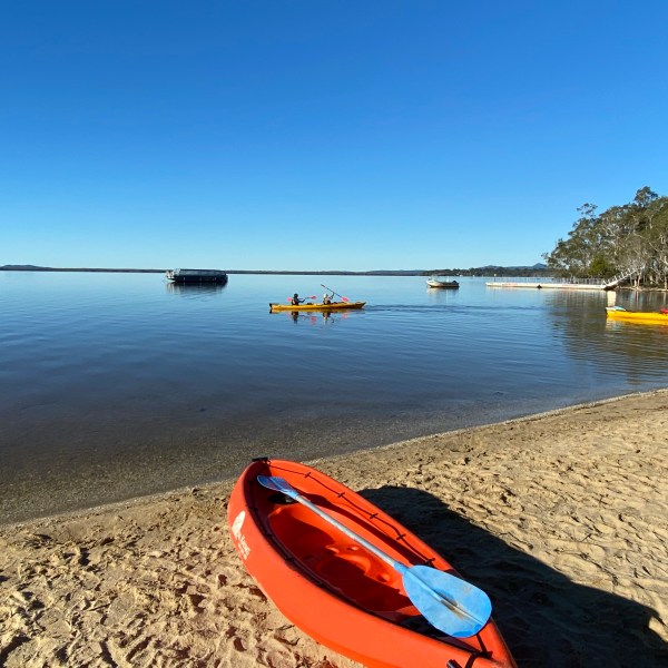 a boat sitting on top of a beach next to a body of water