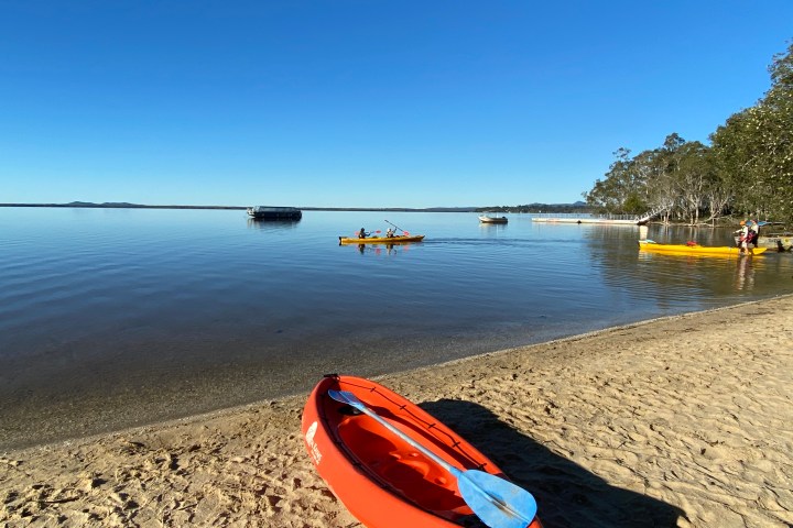 a boat sitting on top of a beach next to a body of water