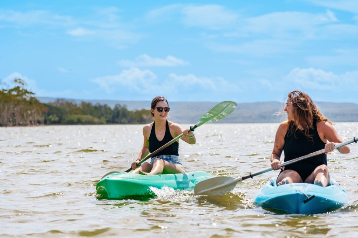 Two women kayaking on a sunny day in open water.